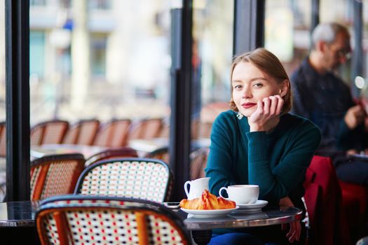 Young elegant woman drinking coffee in traditional cafe in Paris, France