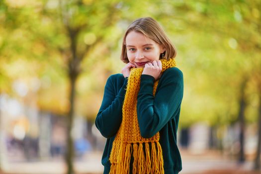Happy young girl in yellow scarf in autumn park on a bright fall day