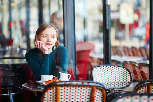Young elegant woman drinking coffee in traditional cafe in Paris, France