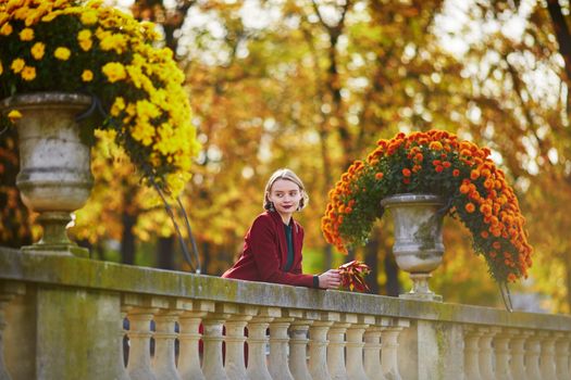 Beautiful young woman with bunch of colorful autumn leaves walking in park on a fall day. Luxembourg garden, Paris, France