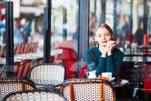 Young elegant woman drinking coffee in traditional cafe in Paris, France