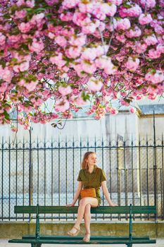 Beautiful French woman walking in Paris on a spring day at cherry blossom season