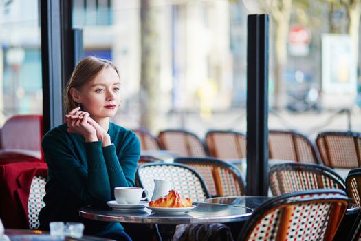 Young elegant woman drinking coffee in traditional cafe in Paris, France