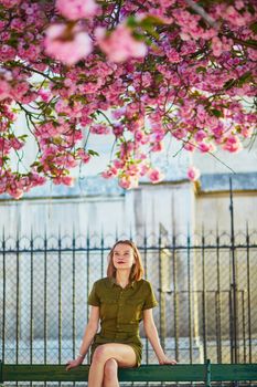 Beautiful French woman walking in Paris on a spring day at cherry blossom season