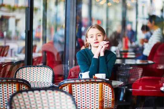 Young elegant woman drinking coffee in traditional cafe in Paris, France