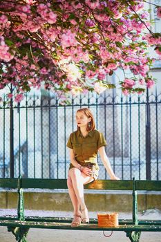 Beautiful French woman walking in Paris on a spring day at cherry blossom season