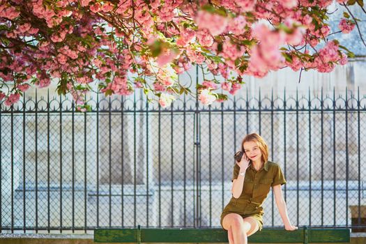 Beautiful French woman walking in Paris on a spring day at cherry blossom season