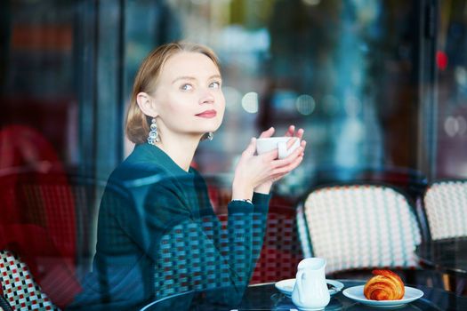 Young elegant woman drinking coffee in traditional cafe in Paris, France