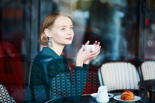 Young elegant woman drinking coffee in traditional cafe in Paris, France