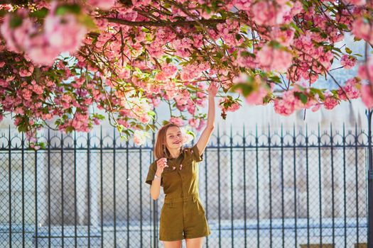 Beautiful French woman walking in Paris on a spring day at cherry blossom season