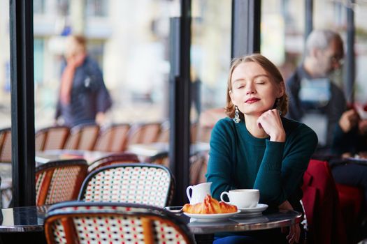 Young elegant woman drinking coffee in traditional cafe in Paris, France