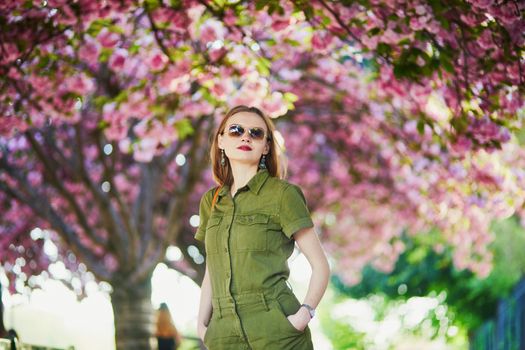 Beautiful French woman walking in Paris on a spring day at cherry blossom season
