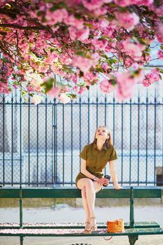 Beautiful French woman walking in Paris on a spring day at cherry blossom season