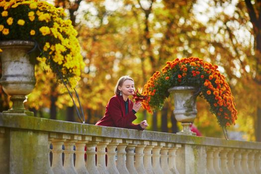 Beautiful young woman with bunch of colorful autumn leaves walking in park on a fall day. Luxembourg garden, Paris, France