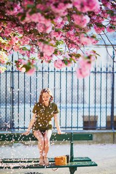 Beautiful French woman walking in Paris on a spring day at cherry blossom season