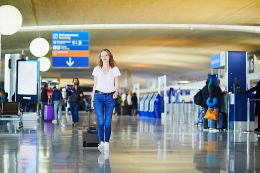 Young woman in international airport walking with luggage, ready for her flight