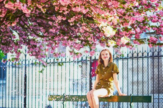 Beautiful French woman walking in Paris on a spring day at cherry blossom season