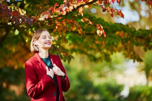 Beautiful young woman with bunch of colorful autumn leaves walking in park on a fall day. Luxembourg garden, Paris, France