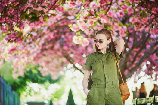 Beautiful French woman walking in Paris on a spring day at cherry blossom season