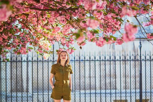 Beautiful French woman walking in Paris on a spring day at cherry blossom season
