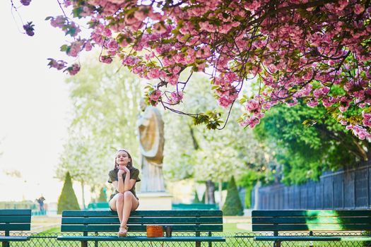 Beautiful French woman walking in Paris on a spring day at cherry blossom season