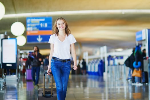 Young woman in international airport walking with luggage, ready for her flight