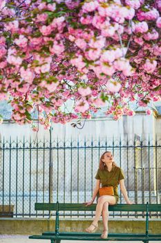 Beautiful French woman walking in Paris on a spring day at cherry blossom season