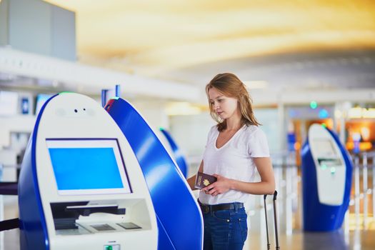 Young woman in international airport doing self check-in