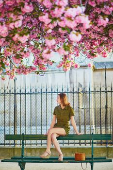 Beautiful French woman walking in Paris on a spring day at cherry blossom season