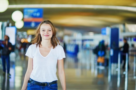 Young woman in international airport walking with luggage, ready for her flight