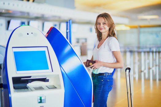 Young woman in international airport doing self check-in