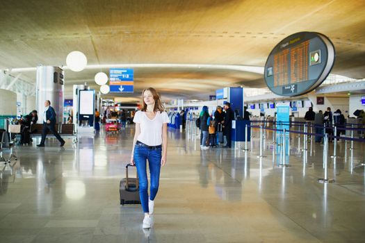 Young woman in international airport walking with luggage, ready for her flight