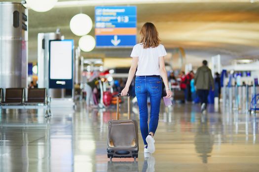 Young woman in international airport walking with luggage, ready for her flight