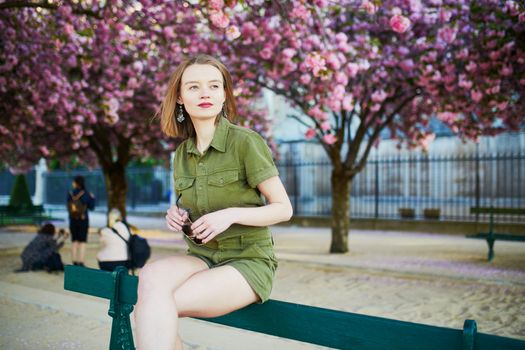 Beautiful French woman walking in Paris on a spring day at cherry blossom season