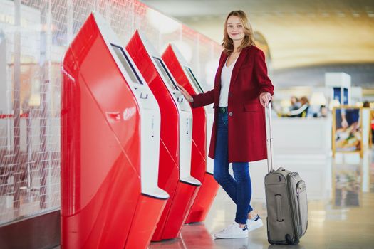 Young woman in international airport doing self check-in