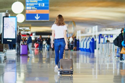 Young woman in international airport walking with luggage, ready for her flight