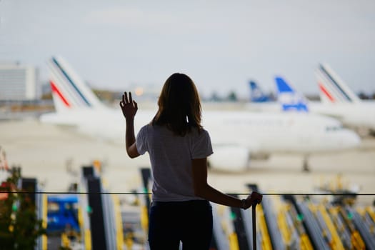 Young woman in international airport, looking through the window at planes