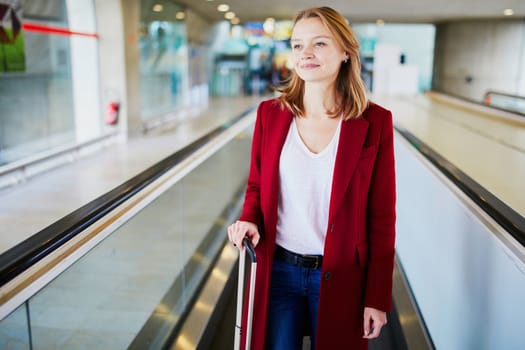 Young woman in international airport with luggage on travelator