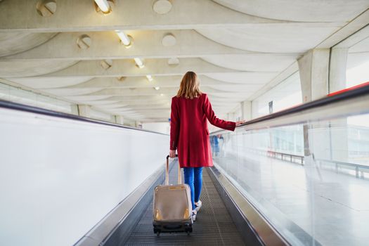 Young woman in international airport with luggage on travelator