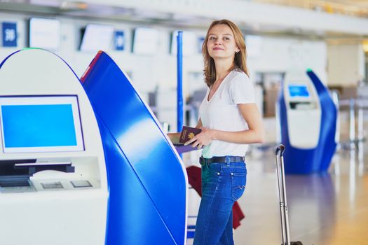 Young woman in international airport doing self check-in