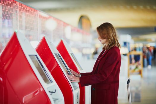 Young woman in international airport doing self check-in