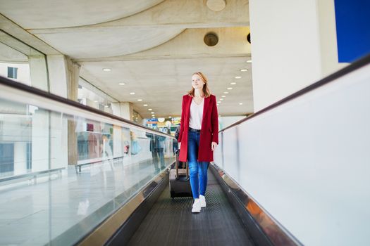 Young woman in international airport with luggage on travelator