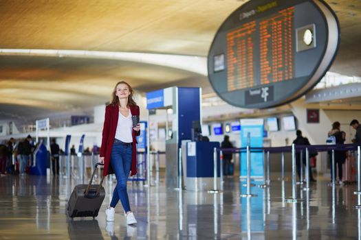 Young woman in international airport with luggage, ready for her flight