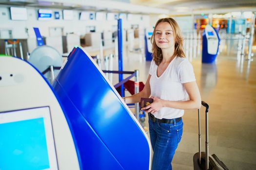 Young woman in international airport doing self check-in