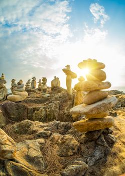 Stones pyramid on sand symbolizing zen, harmony, balance. Ocean at sunset in Khao Lak Thailand