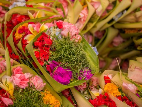 Traditional balinese offerings to gods in Bali with flowers and aromatic sticks