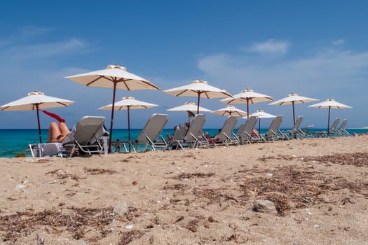 Tourists relaxing on sunlounger on the beach on Lefkada island, Greece