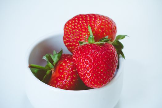 A pile of strawberries in a white bowl