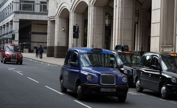 A London taxi cab driving pass a queue of stationary taxi cabs in the heart of London