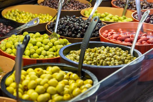 Bowls of green and black olives on display on a stall